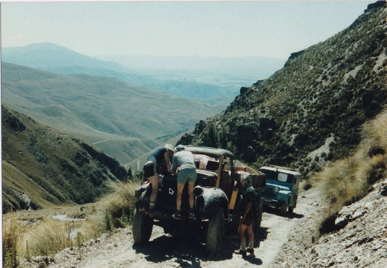 The GMC truck on the winding access road, with a Land Rover following behind